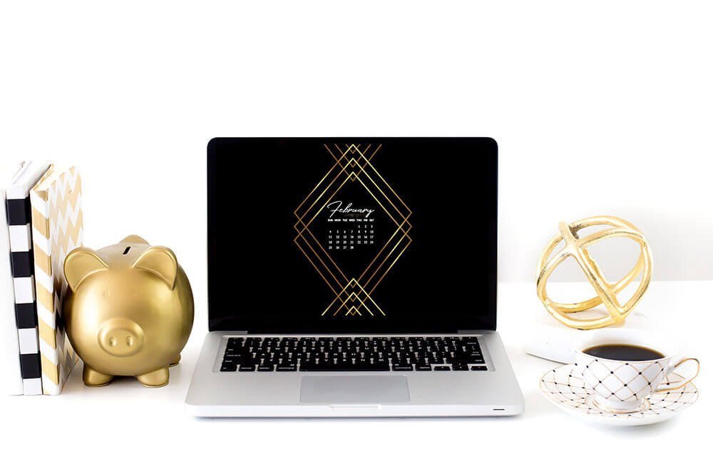laptop with black and gold February calendar mock up. gold pig piggy bank.